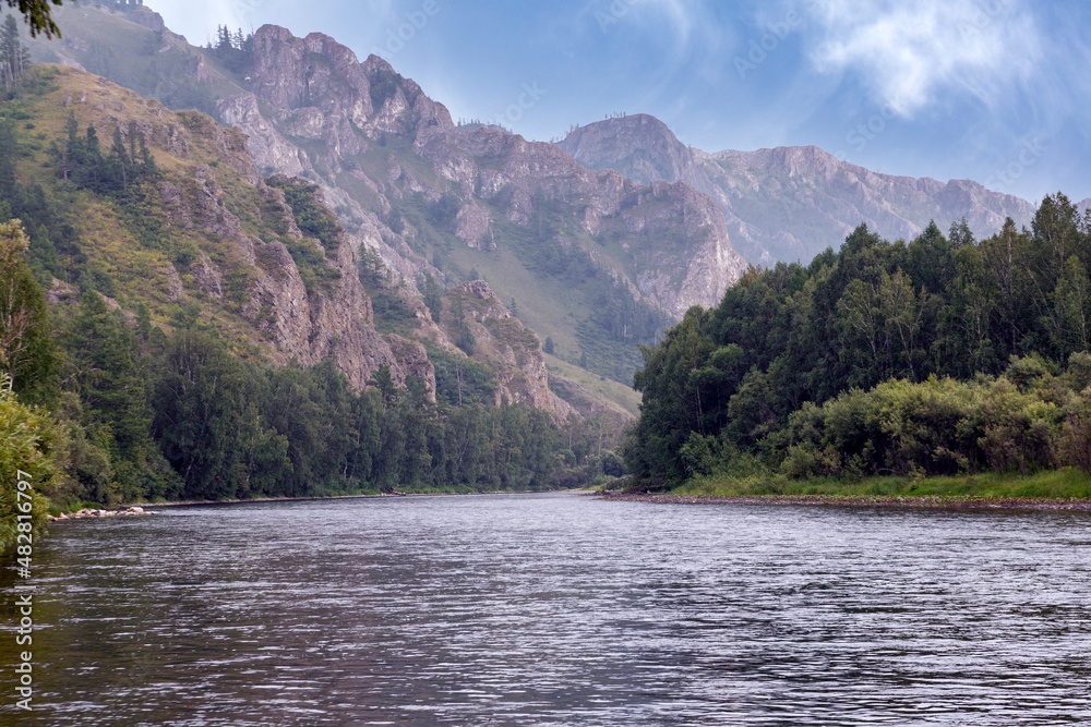 A river and forested mountains along its banks. Summer landscape, beauty of nature. A river and forested mountains along its banks. Summer landscape, beauty of nature.
