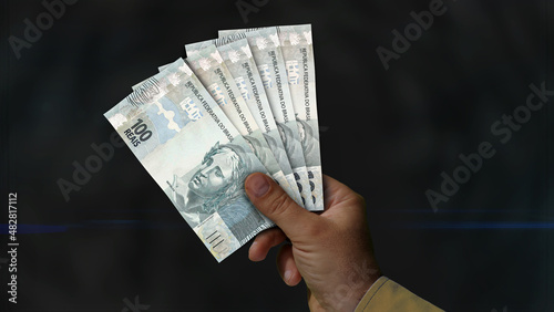 Brazil Real, Reai pile of money in hand 3d illustration. BRL banknotes background concept of finance, economy crisis, inflation and business. photo