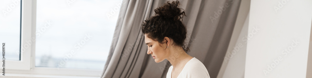 Fototapeta premium The woman looking at the phone while sitting on the bed in a room