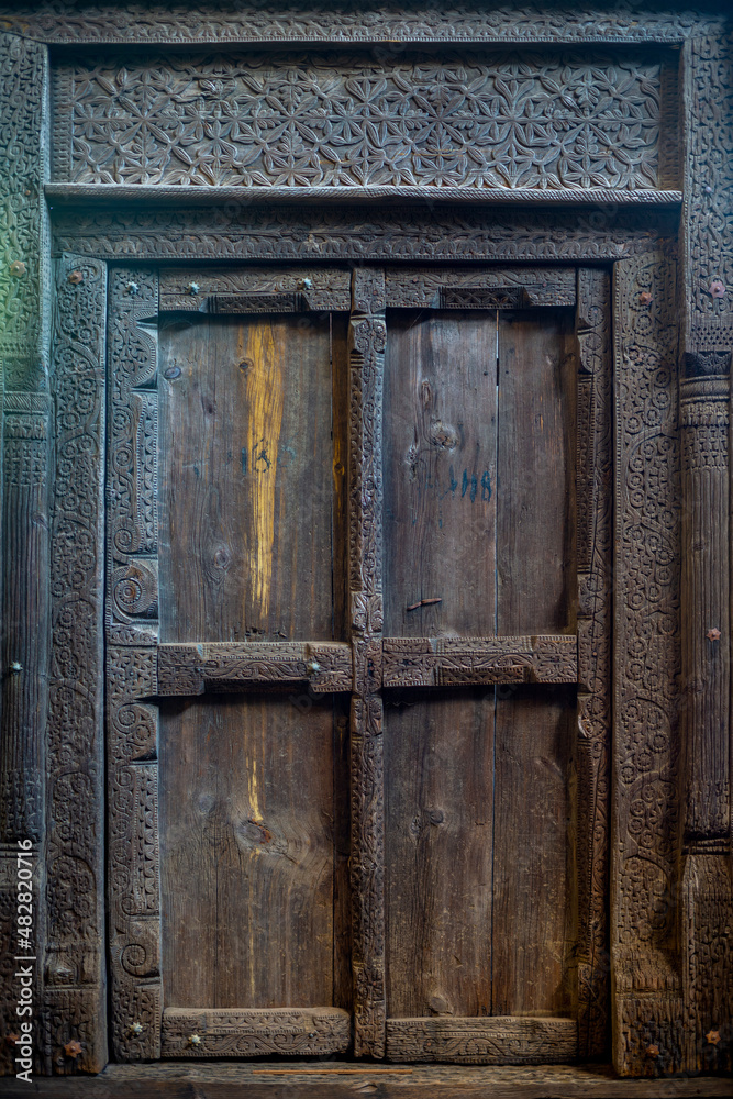 Indian wooden old door vintage texture background. Front view of Ancient Mughal Art Door doors made of authentic material in an old building entrance. Weathered wood carved door in India