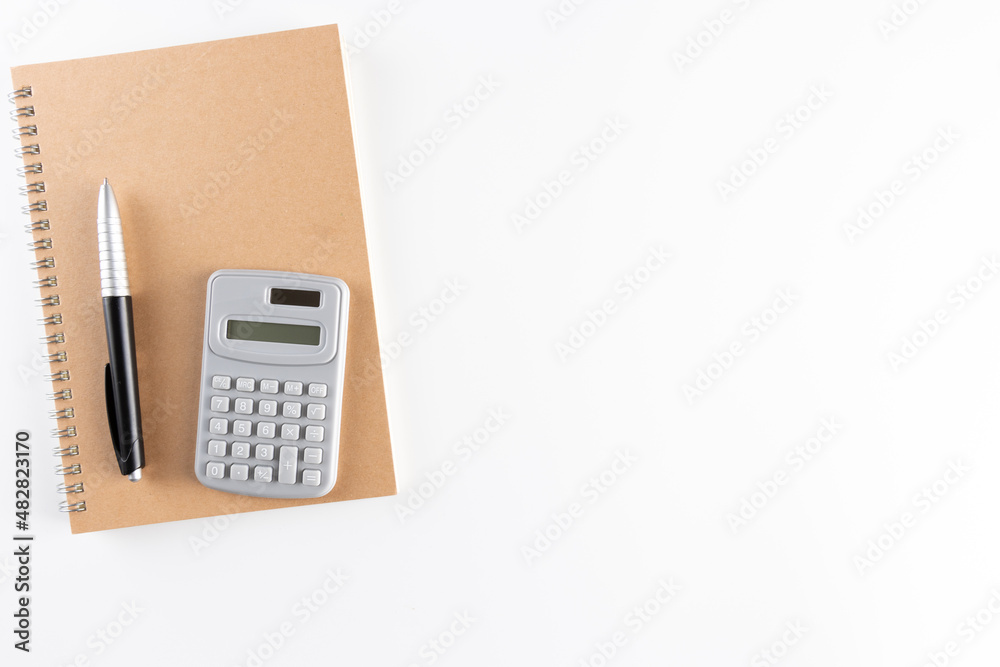 cardboard brown coloured Notebook, calculator and pen isolated on white background. Empty blank space for copy space. business and educational concept. cardboard brown coloured Notebook, calculator and pen isolated on white background. Empty blank space for copy space. business and educational concept.