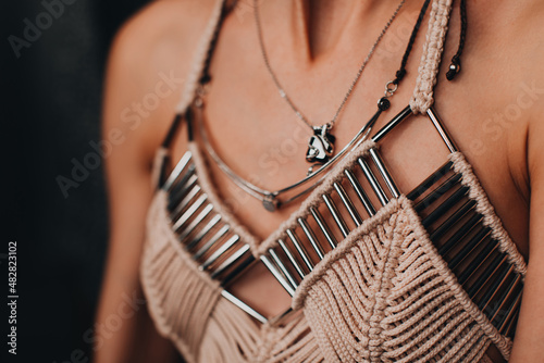 Part of a female body dressed in an elegant beige boho top with silver details. Women's fashion and accessories