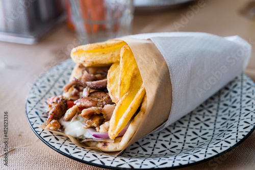 Traditional Greek food gyros pita with fries, vegetables and tzatziki sauce. photo