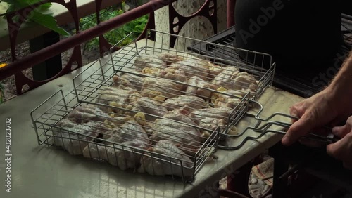 Man's hands closes the grate and puts a grill with chicken on mangal. Outdoor picnic in nature. Sunshine. Close-up.