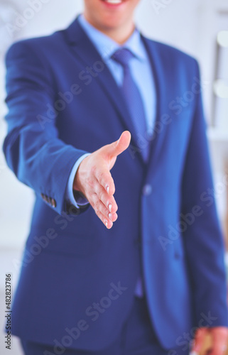 Business and office concept - handsome businessman with open hand ready for handshake