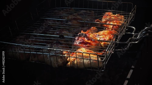 Close-up shot of cooking chicken on cover charcoal. Baking and roasting marinated legs and wings on barbecue grill.