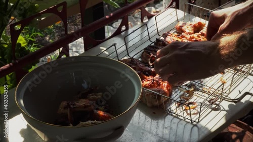 Chef placing pieces of fried chicken wings into deep dish, freshly cooked on a bonfire