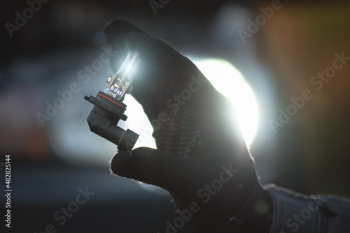 A light bulb of car headlight in auto electrician hand close up.