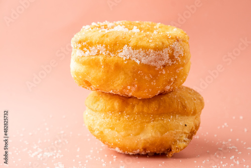 Two portuguese malasada donuts sprinkled with sugar on a pink bright background. photo