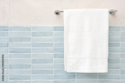 White fluffy bath towel hanging on wall rail in bathroom photo