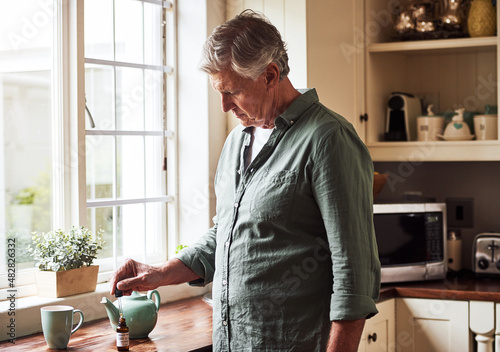 Just a little drop. Cropped shot of a relaxed senior man preparing a cup of tea with CBD oil inside of it at home during the day.