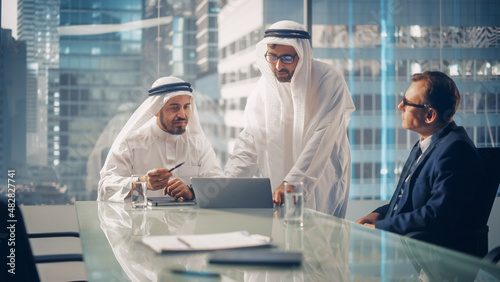 International Business Consultant Advises on Financial Strategy Plan to Successful Arab Company Owners. Multicultural Meeting in Modern Office Between American and Saudi Businessman. photo