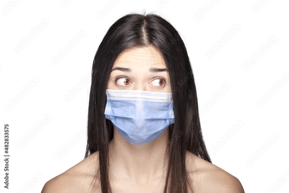 Portrait of a brunette girl wearing medical mask over her mouth and nose. Curious face expression. Portrait of a brunette girl wearing medical mask over her mouth and nose. Curious face expression.