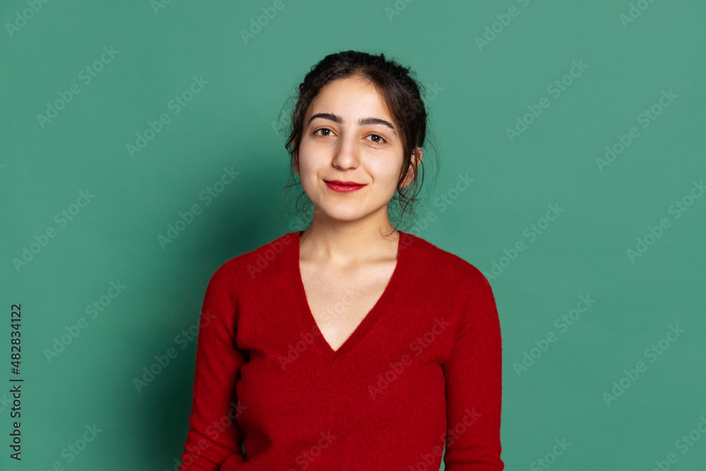 Obraz premium Studio shot of young pretty girl in red pullover isolated on green background. Concept of emotions, facial expressions