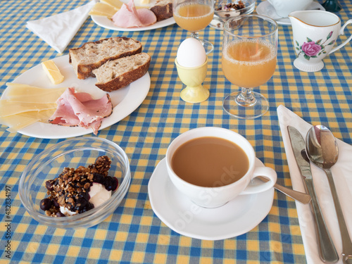 European breakfast with filtered coffee, egg, juice, bread, ham, cheese, granola and yogurt