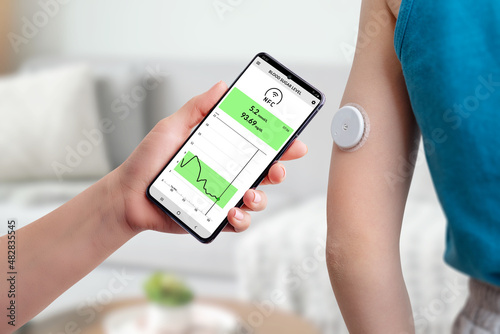 Measurement of blood glucose with the help of mobile app and sensor. Hand brings the phone closer to the sensor located on the child\'s hand concept