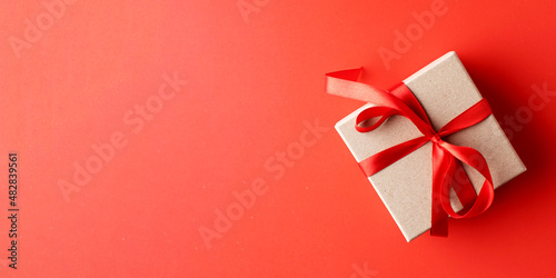 Gift box with a red ribbon on a red background. Copy space.