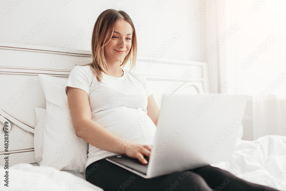Pregnant woman working on laptop at home Pregnant woman working on laptop at home