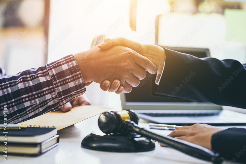 Young lawyer and a client shake hands after agreeing to legal work. Young lawyer and a client shake hands after agreeing to legal work.