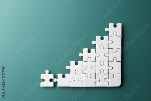 white puzzle jigsaw in graph shape on green background , business concept