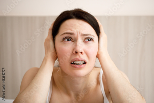 The woman covers her ears because of the loud noise. Noisy neighbors listen to loud music and interfere with sleep. Using earplugs.
