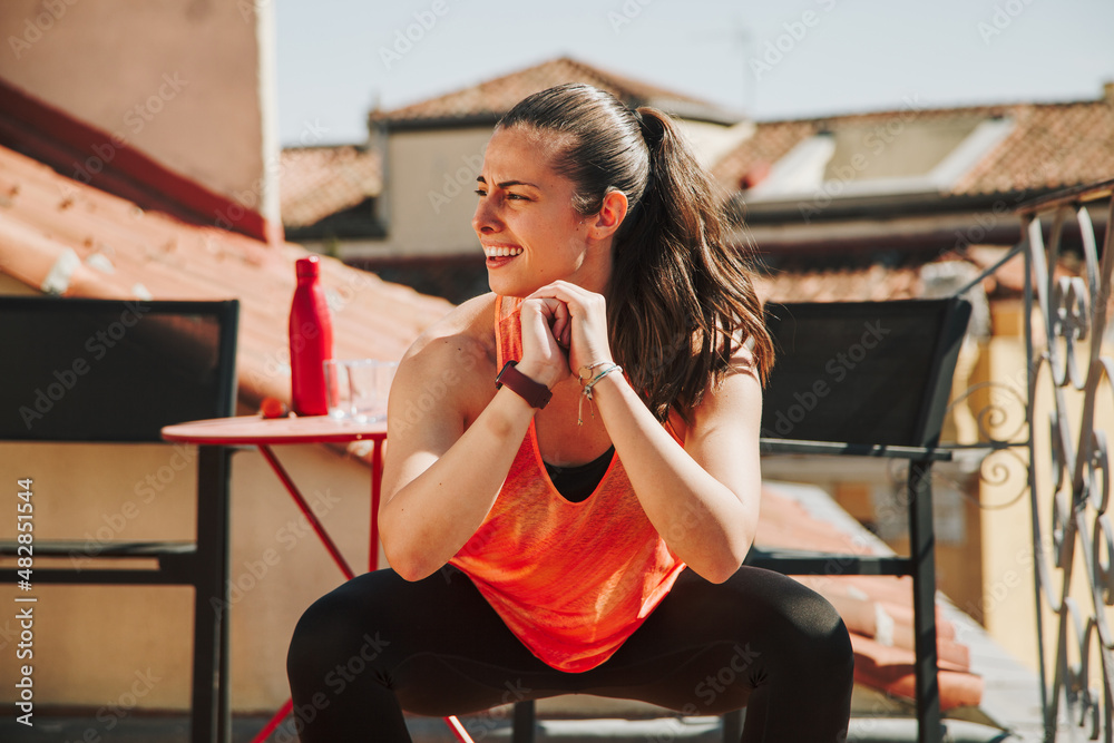 Woman working out on a building rooftop terrace, doing squats
