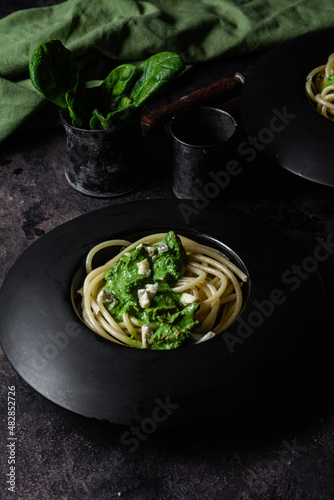 Pasta with spinach sauce on a black plate
