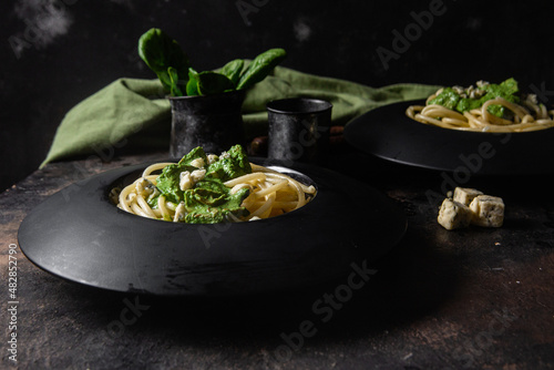 Pasta with spinach sauce on a black plate