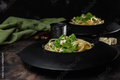 Pasta with spinach sauce on a black plate