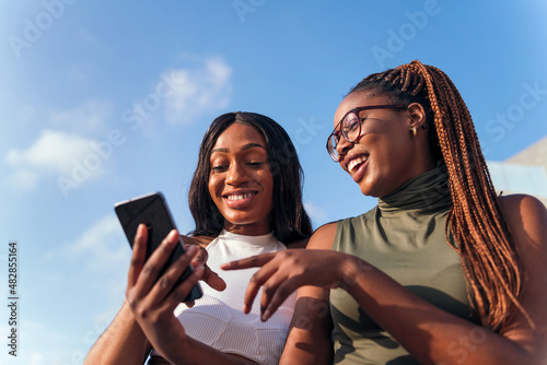two young african women having fun looking phone
