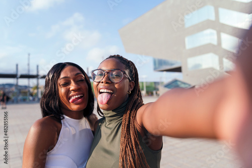 two friends sticking out tongues to take a selfie