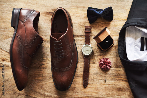 All set for the big day. Still life shot of formal shoes alongside a suit and other accessories on a wooden surface.