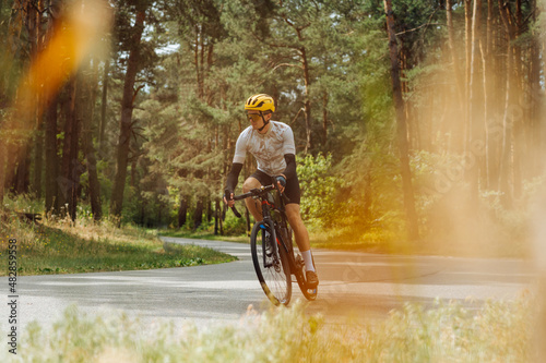 Active young man cyclist rides on a mountain road in the woods on a bicycle.