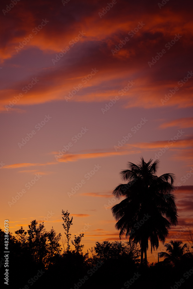 Obraz premium Impressive clouds of red and orange colors during sunrise on the beach.