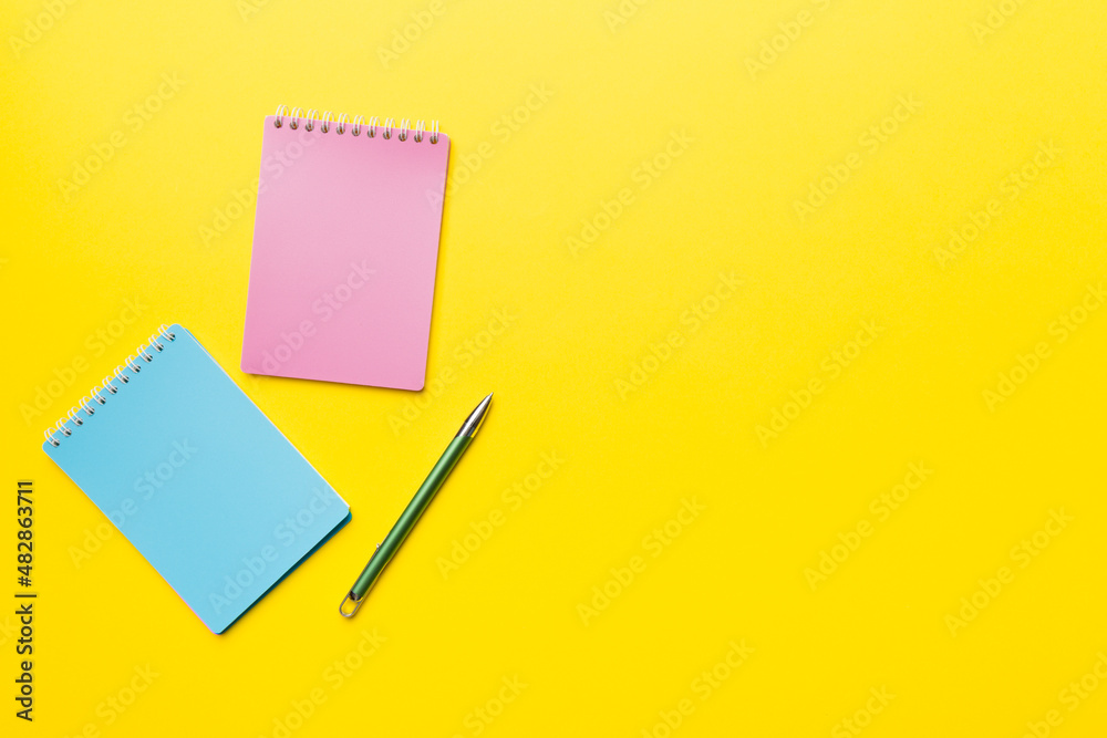 two school colored notebook on a desk background, spiral craft notepad on a table Top view