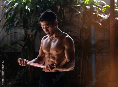 Young man with fit and firm body,holding esistance band in hands prepare for stretching muscle, photo