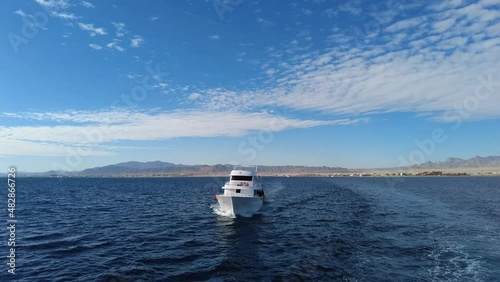 Safaga, Hurghada, Egypt - December 2021: Excursion yacht sails on the red sea with mountains in the background. photo