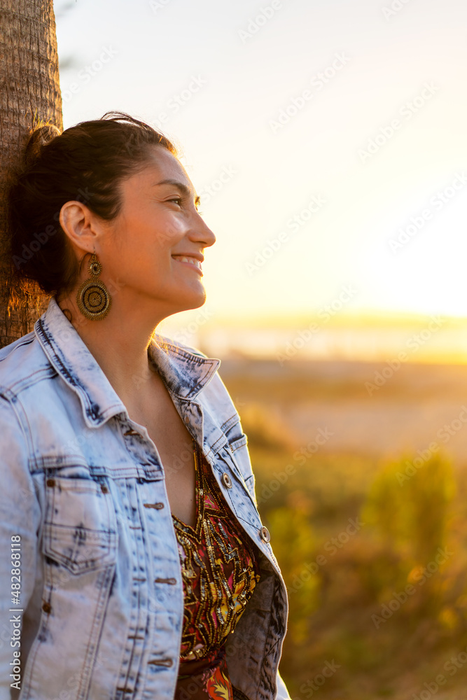 young latin woman smiling happy on the beach at sunset portrait.