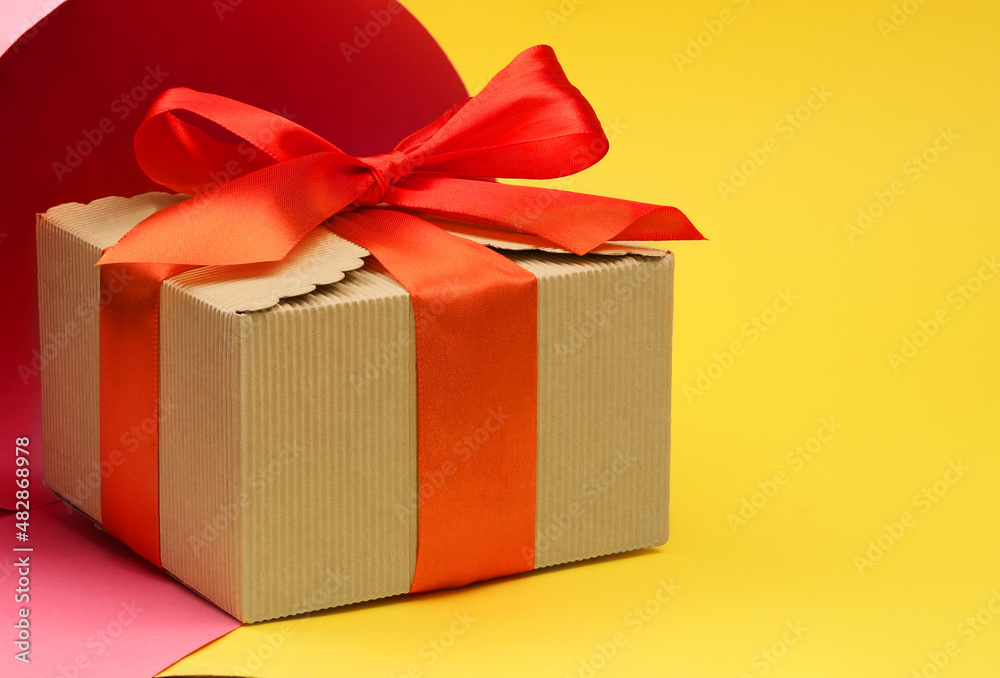 Obraz premium Gift cardboard box with a red bow on a multi-colored background