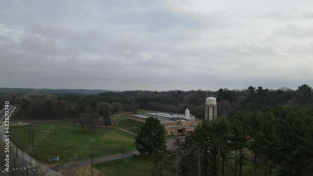 View of valley in Wisconsin with water tower and lush forest land on a gray, cloudy day. Buildings tucked into the landscape to blend in. Highway leading to nowhere. View of valley in Wisconsin with water tower and lush forest land on a gray, cloudy day. Buildings tucked into the landscape to blend in. Highway leading to nowhere.