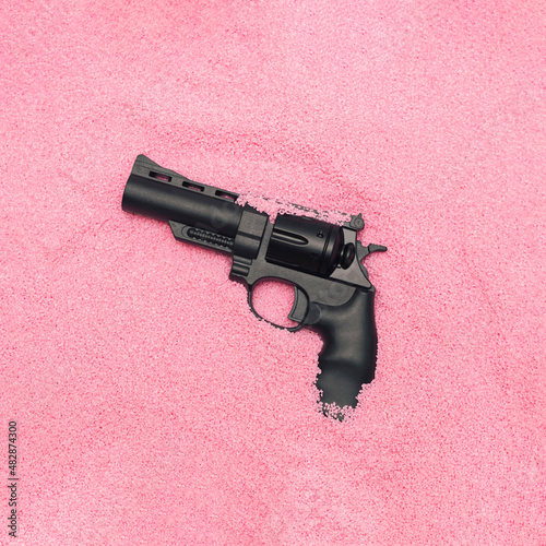 MInimal Valentine hate concept with weapon in pastel pink sand. Modern romantic aesthetic. photo