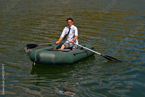 A man in a white shirt on an inflatable boat. Businessman with laptop resting on the lake. The concept of remote work, leisure and freelance.