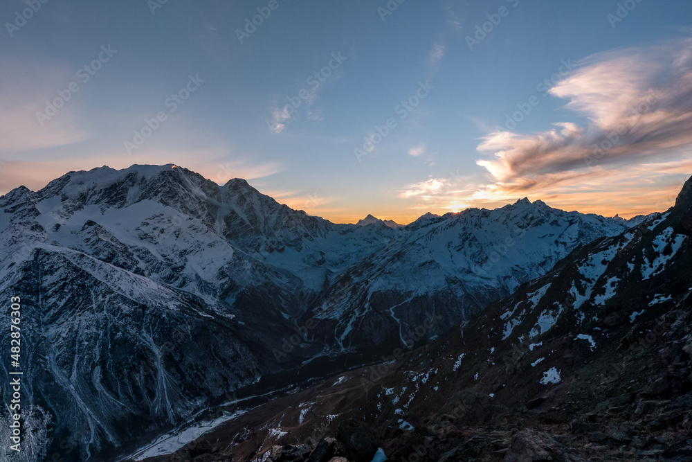 Beautiful colorful sunset sky. Panoramic view of mountain range of the Caucasus Mountains. View from the top of the mountain. Elbrus region