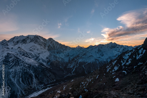 Beautiful colorful sunset sky. Panoramic view of mountain range of the Caucasus Mountains. View from the top of the mountain. Elbrus region