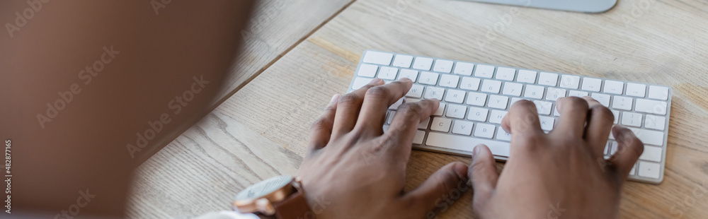 cropped view of african american man typing on computer keyboard, banner. cropped view of african american man typing on computer keyboard, banner.