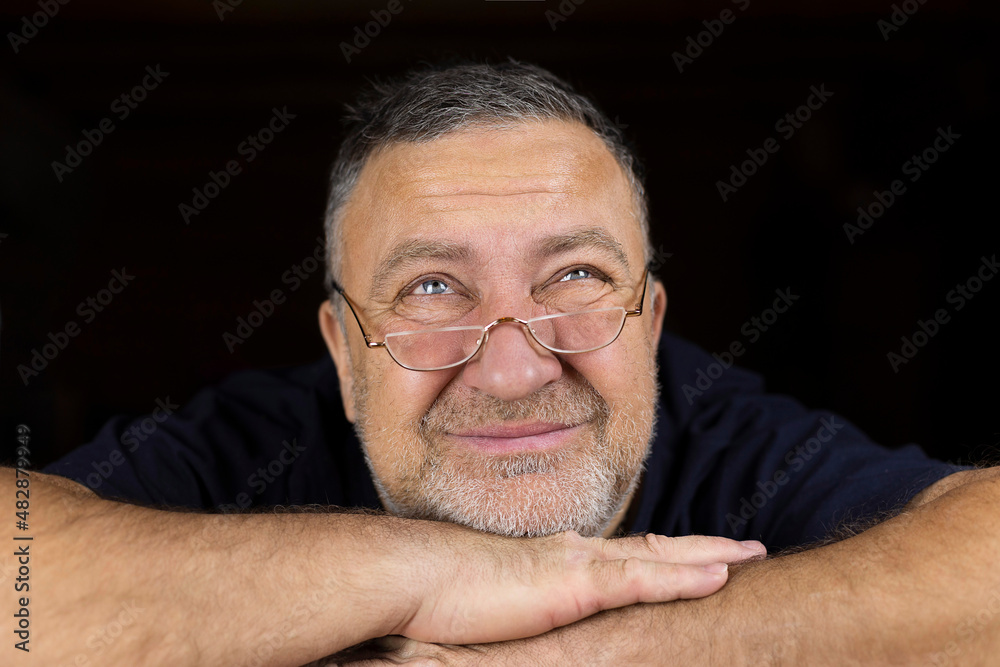 Fototapeta premium The face of a mature man with glasses with a strange look up. Soft focus.