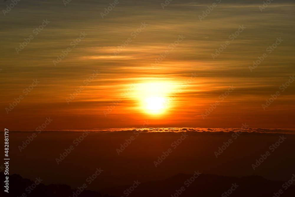 The sun set behind thick forests followed by mountains. The sun set behind thick forests followed by mountains.
