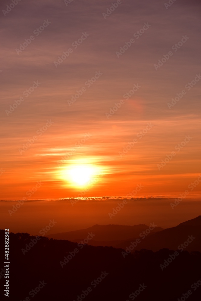 The sun set behind thick forests followed by mountains. The sun set behind thick forests followed by mountains.