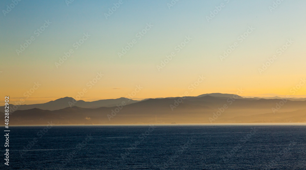 Sea, mountains in the fog at sunset.