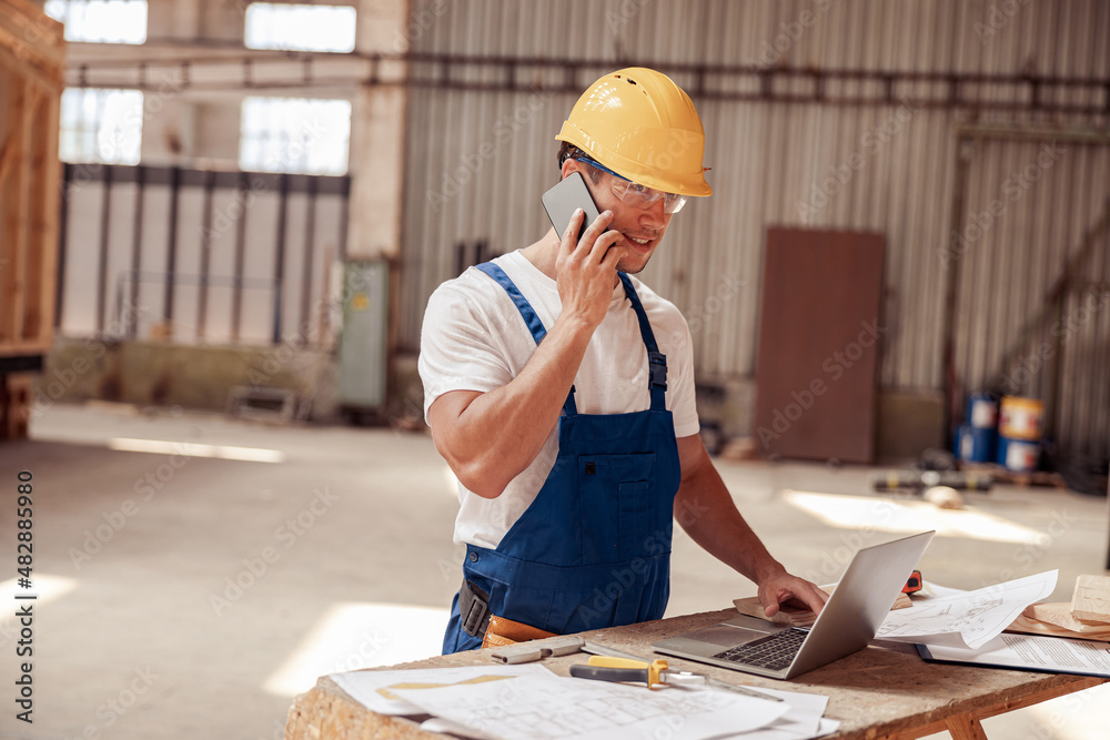 Handsome man builder talking on mobile phone at work Handsome man builder talking on mobile phone at work